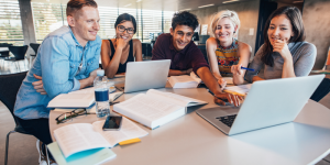 A diverse group of university students studying together with laptops and books.