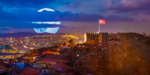 A scenic view of Ankara Castle at night with the Turkish flag flying over the illuminated city.
