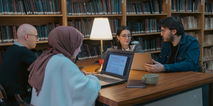 A group of university students studying together in a library, engaged in a discussion.