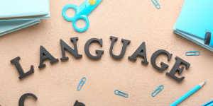 The word “Language” placed on a table surrounded by school supplies, symbolizing language learning