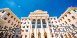 A modern university building with a blue sky background, representing Turkish higher education.