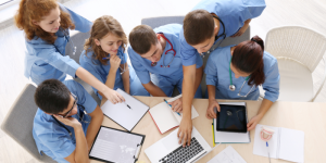 A group of medical students studying together with digital tools and textbooks.