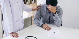 A concerned student with a doctor offering comfort in a medical consultation setting.